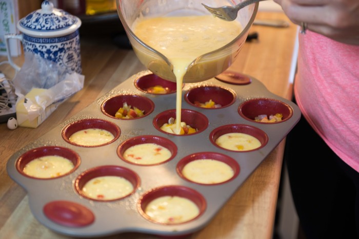 Ham and cheese egg cups pouring egg